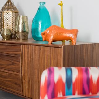 A mid-century modern cabinet with colourful ornaments atop