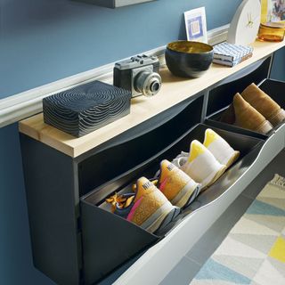 Black and wooden wall-mounted opened storage with shoes and counter-top décor