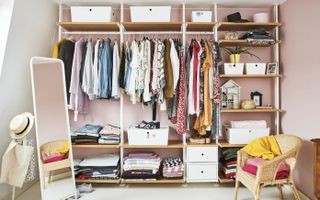 A wardrobe system with clothes and accessories put against wall with pink wall paint decor