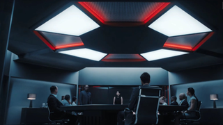 Resident Evil umbrella logo on ceiling above meeting table surrounded by Umbrella Corp staff