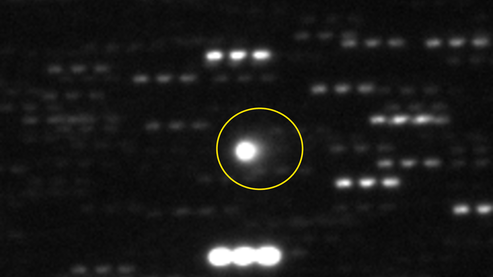 A blurry photo of a comet in the sky with a ring around it