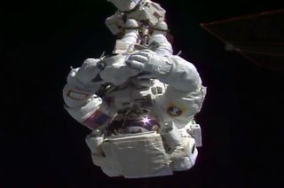 Expedition 55 flight engineer Ricky Arnold riding on the end of the Canadarm2 robotic arm outside of the space station.