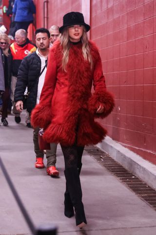 Taylor Swift wears a purple fur coat and black hat to a Kansas City Chiefs game on December 21, 2024.