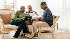 An older couple talk with their financial adviser in their living room.