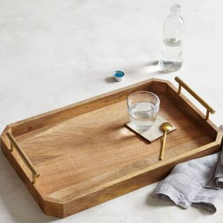 A wooden decorative tray with gold handles from West Elm