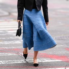 Woman in a denim skirt and black flats GettyImages-2004568154