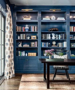 traditional home office with dark blue built in shelving and black desk