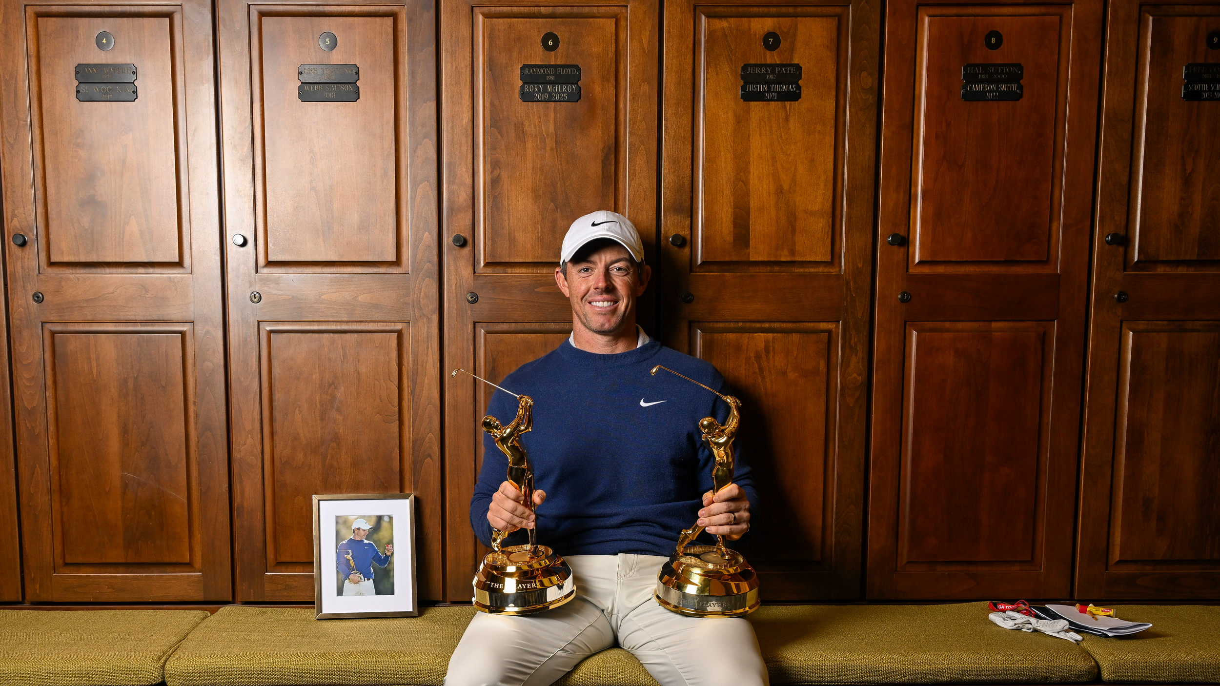 Rory McIlroy sat by his locker at TPC Sawgrass holding his two Players championship trophies