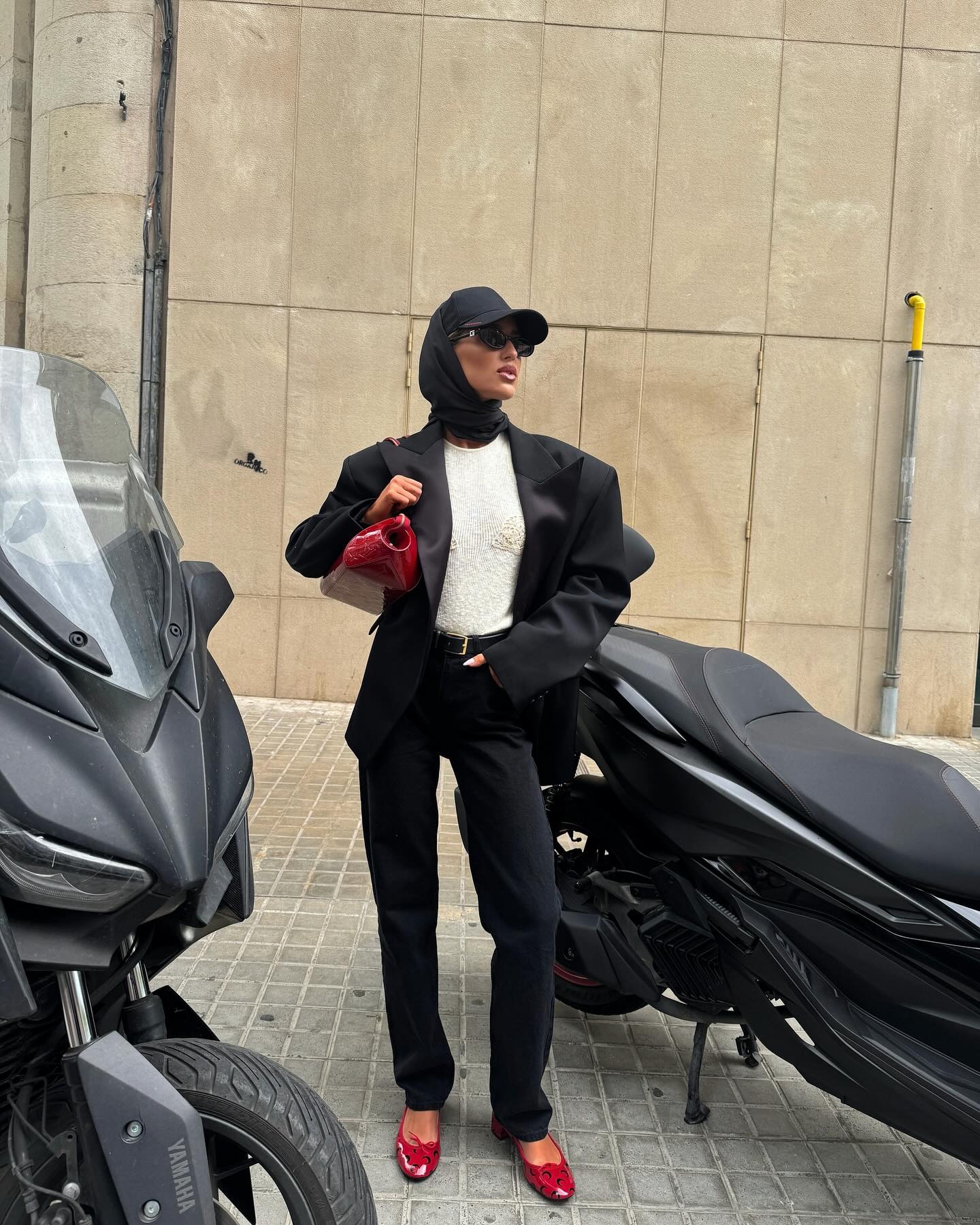 Emili Sindlev wearing a black outfit with red ballet flats.