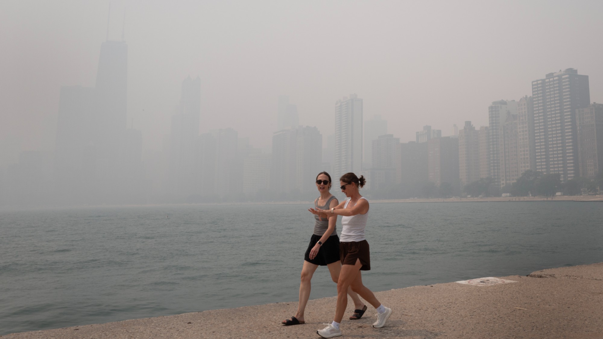 CHICAGO, ILLINOIS - JULY 16: People walk along Lake Michigan as smoke from Canadian wildfires blankets the city on July 16, 2026 in Chicago, Illinois.