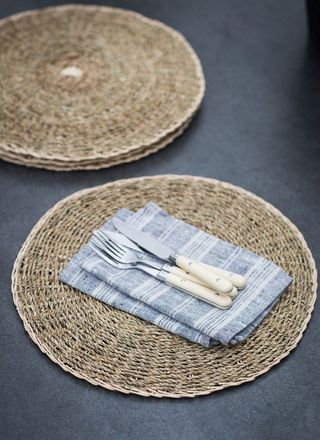 Garden Trading Seagrass woven Placemats on a dark grey table with white and blue napkins