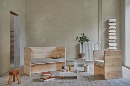 Wooden sofa and chair in a plastered room with book stack shelf and radiator