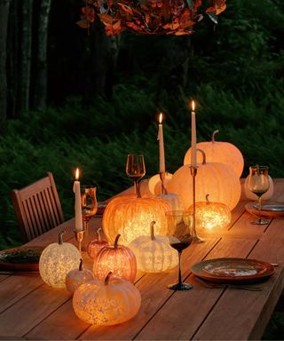 Light up pumpkins grouped together to decorate a wooden outdoor table