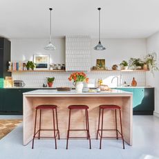 White and green kitchen with wooden kitchen island and red kitchen bar stools