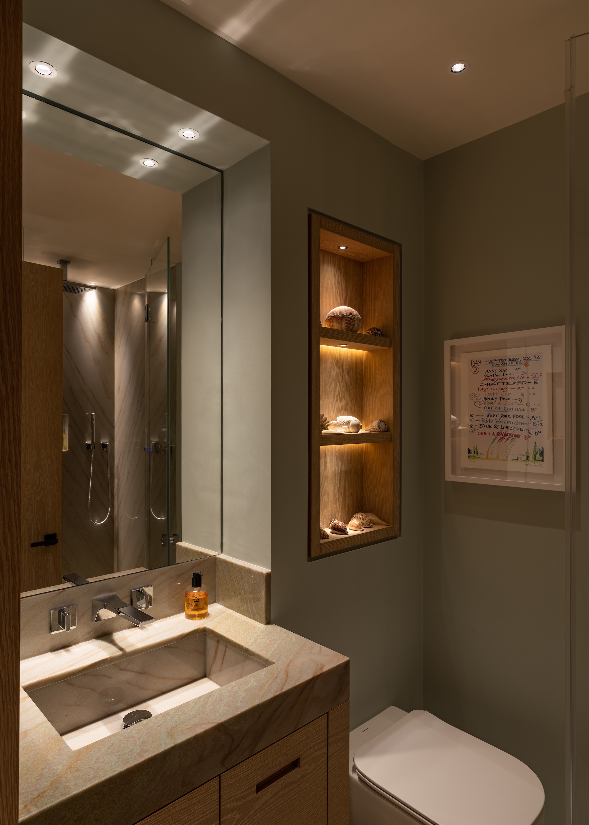 A bathroom with dimmable lighting switches in different parts of the space as well as a basin with a large mirror above it.