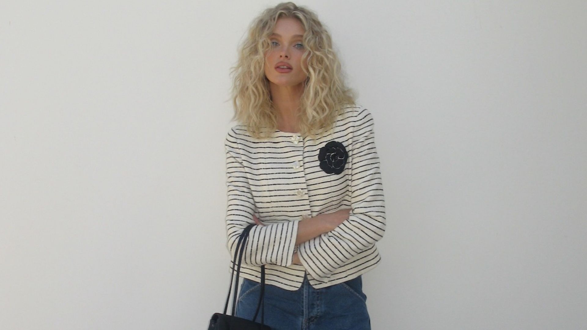 Elsa Hosk poses for a photo wearing a striped cropped jacket with wide-leg jeans and white pointed-toe heels.