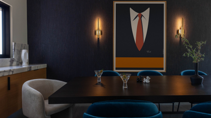 A dramatic intimate blue dining room with wall lights and dark walls