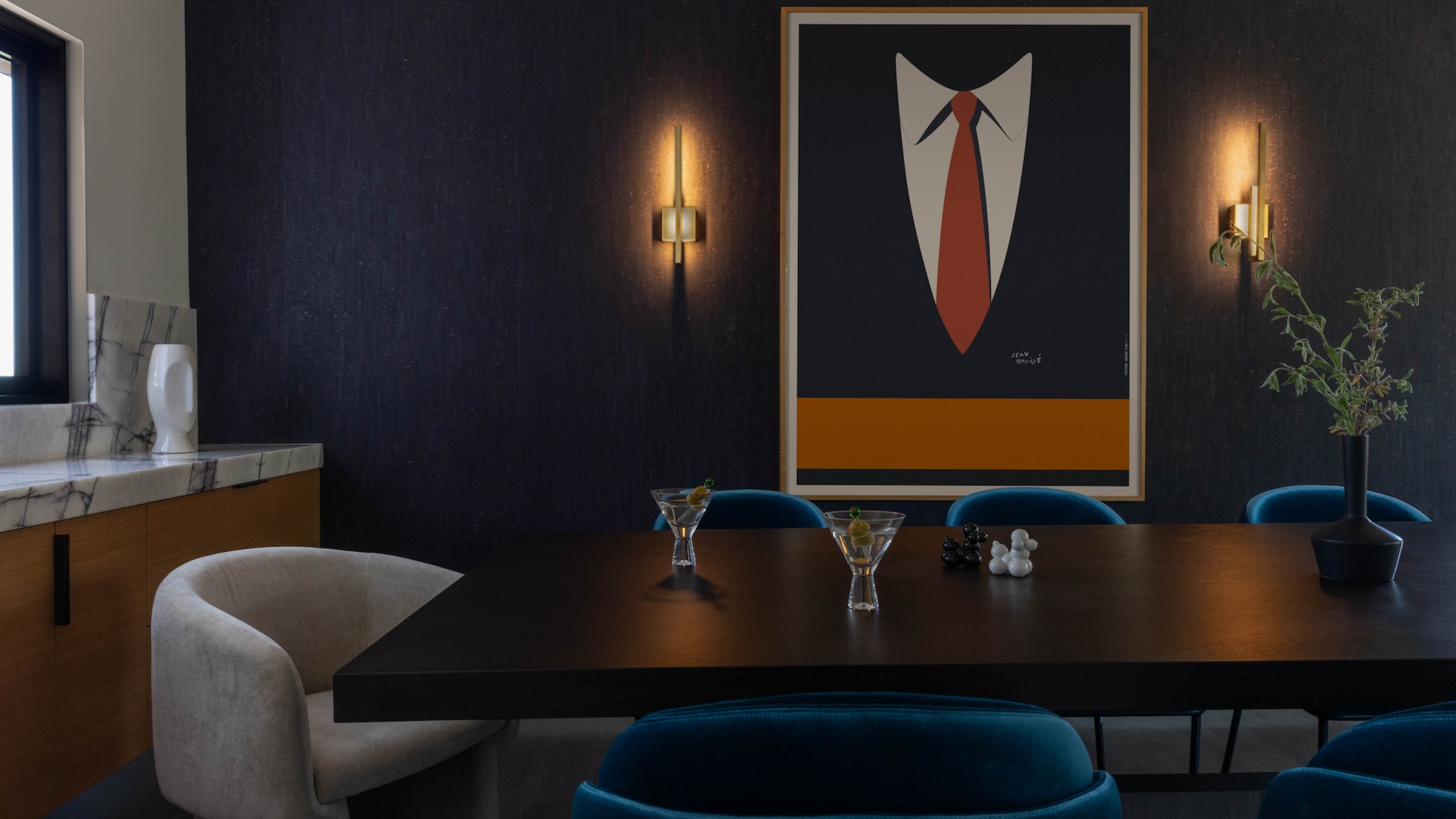 A dramatic intimate blue dining room with wall lights and dark walls