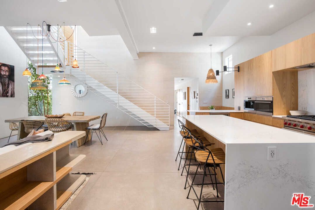 An open plan living space with a large white staircase and a rectangular dining table