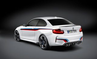 A 3 door BMW M2 in white featuring a red, black and blue stripe along the car's side.