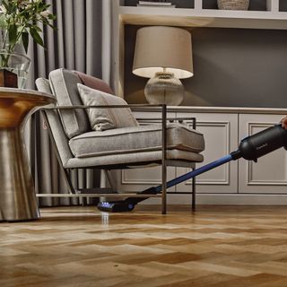 cordless vacuum cleaning wooden floor under chair