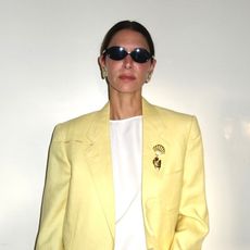 Influencer Jen Wonders wearing a yellow blazer, and gold shell brooch
