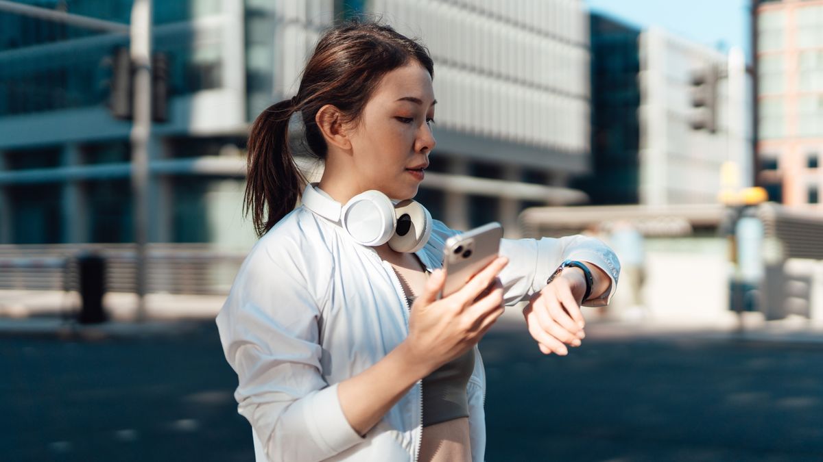 Woman checking sports watch and phone after workout