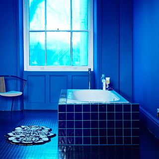 blue bathroom with bathtub and white window