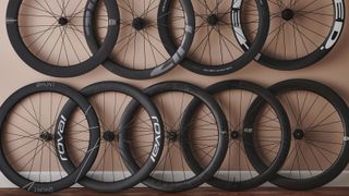 Nine of the best road bike wheels are hung against a terracotta wall