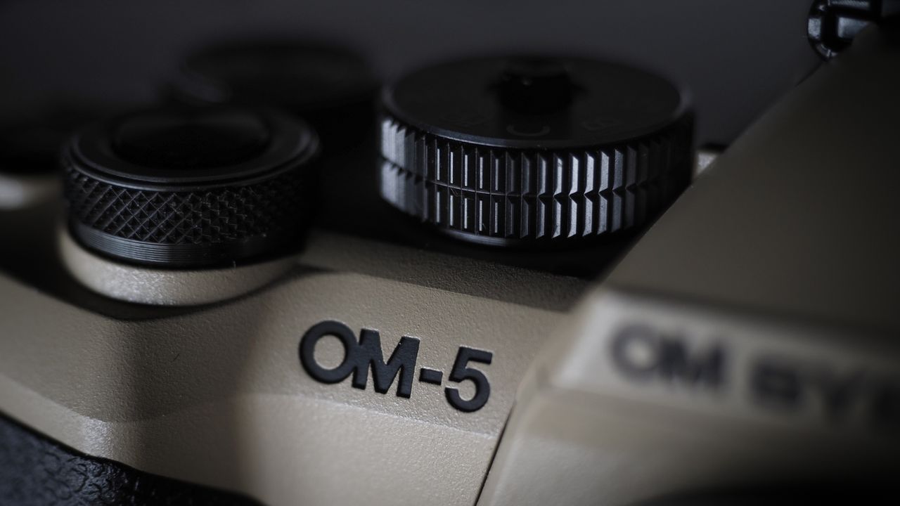 OM System OM-5 Mark II on a wooden surface with an Olympus M.Zuiko 12-45mm lens