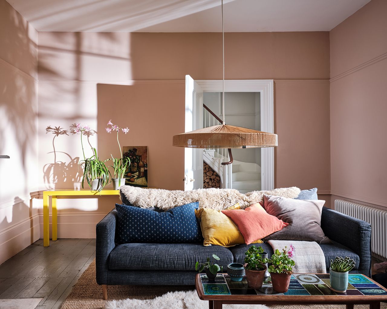 A classic living room with Setting plaster wall paint decor by Farrow & Ball with denim upholstered sofa, cushions and faux fur throw