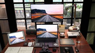 Mac laptop, PC and tablet on desk with other tech