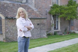 Sarah Beeny stands in the garden outside a house in the country
