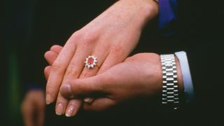 A close up of the hands of Prince Andrew and Sarah Ferguson after the announcement of their engagement at Buckingham Palace, London, 17th March 1986. Ferguson's white and yellow gold engagement ring features a Burma ruby, surrounded by ten drop-diamonds.