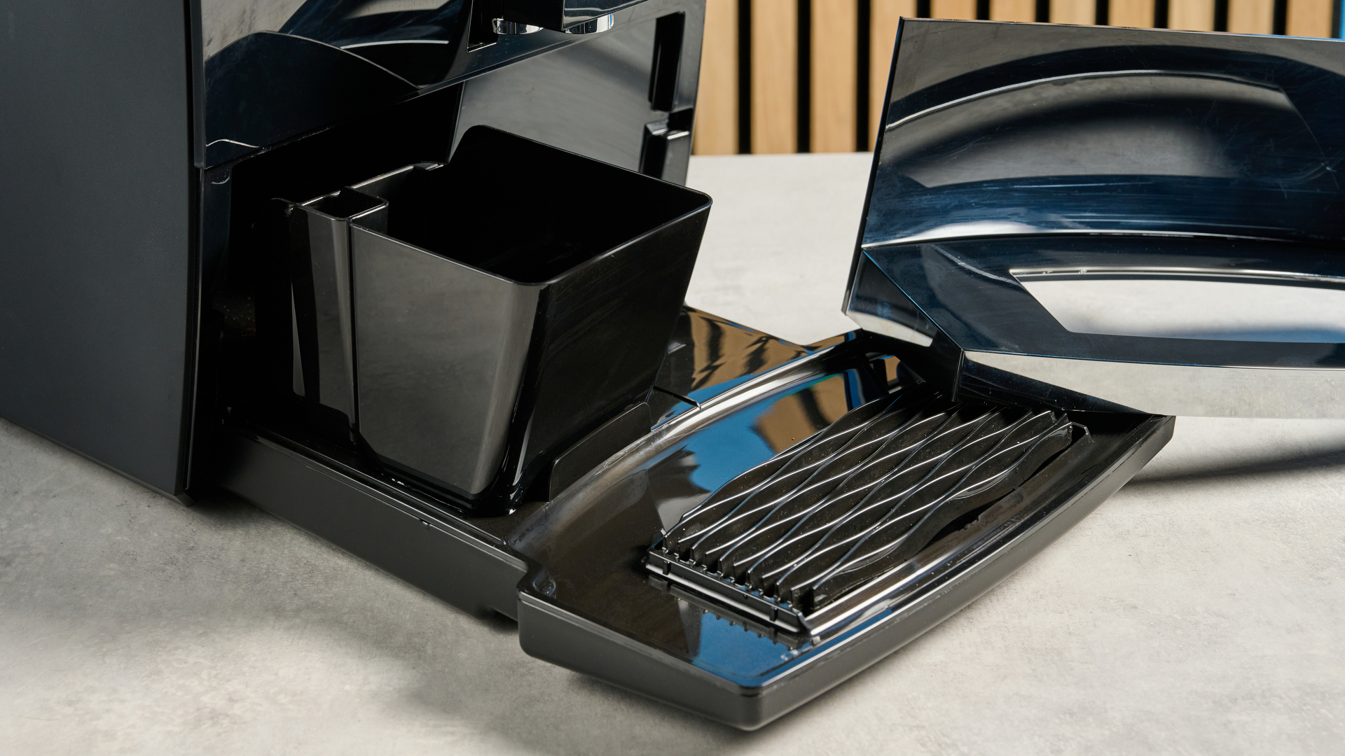 the jura c8 automatic coffee machine in piano black photographed with a blue and wood background