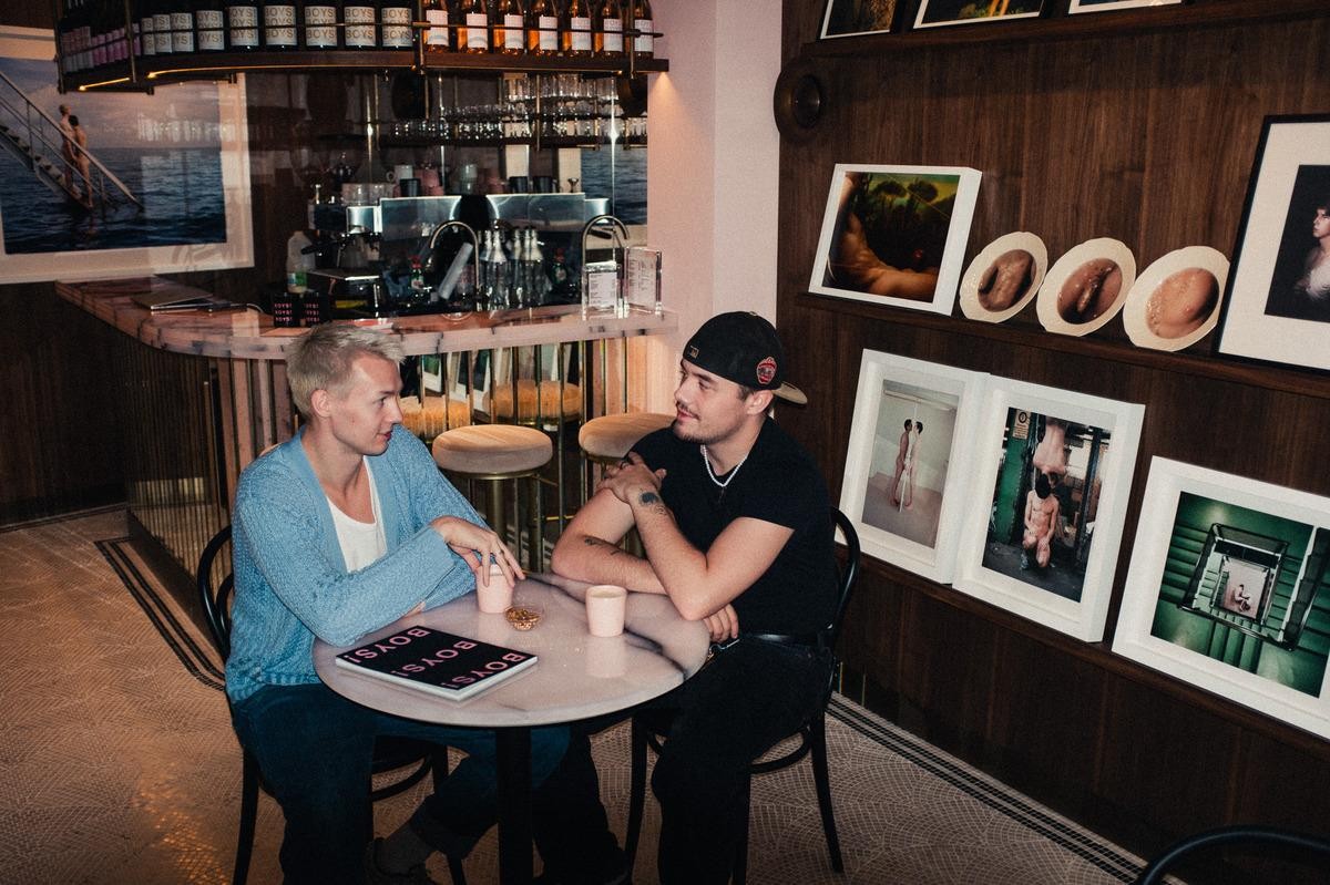 Two young boys sitting at a marble-topped table in a bistro-style bar and gallery.