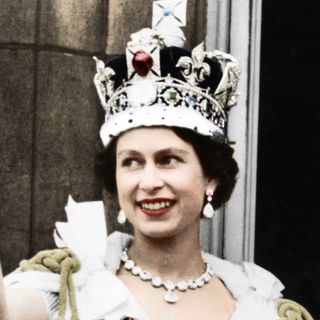 Queen Elizabeth waves from the Buckingham Palace following her Coronation while wearing the heavy Coronation Crown and wearing her Coronation regalia