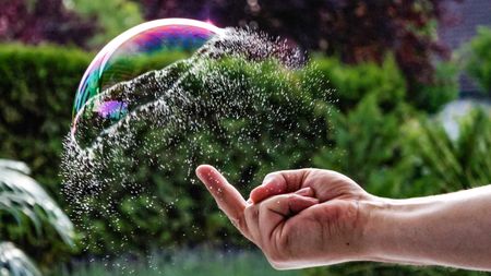 Big soap bubble in moment of bursting due to finger looking like jellyfish.