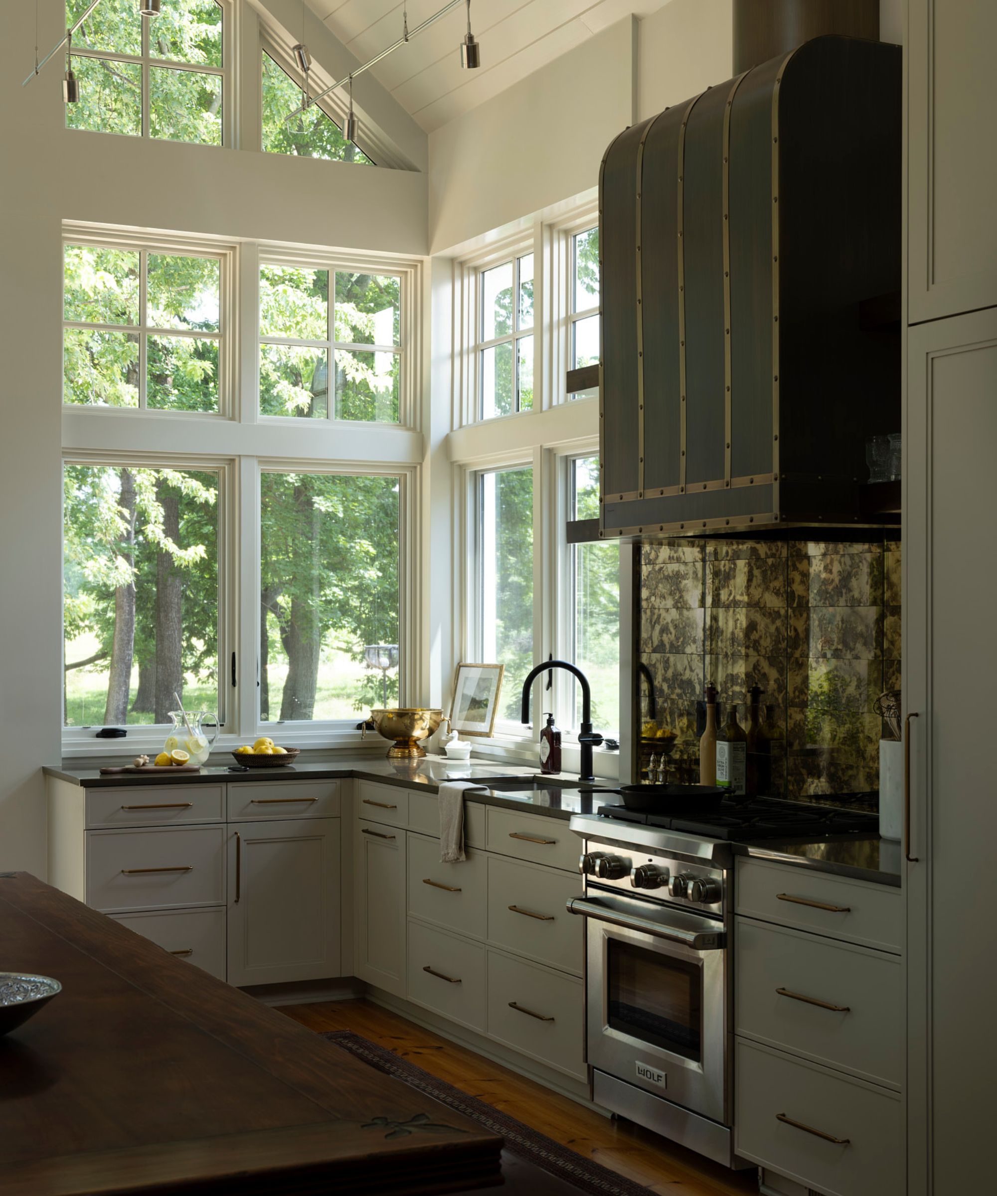 A light green kitchen with slim hardware and brass details