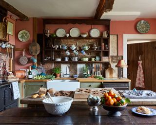 farmhouse kitchen with rustic shelving, green units, and light terracotta walls