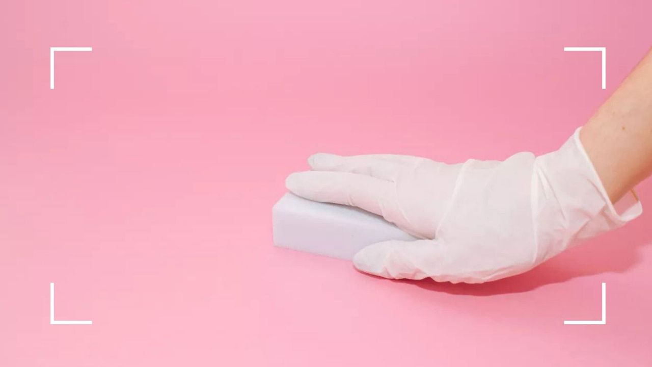 woman&#039;s hand using a magic eraser—to illustrate how to use a Magic Eraser