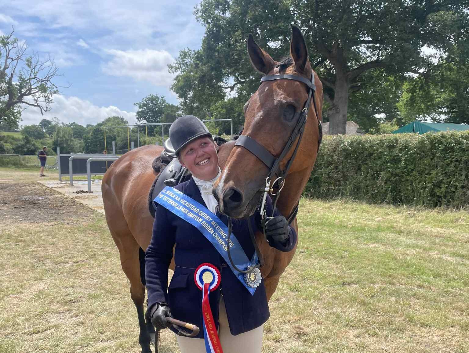 Victoria Bertorelli stands next to An Cathaoir, a one-eyed ex-racehorse fr a photo with their rosette and sash after winning the amateur RoR championship at Hickstead.