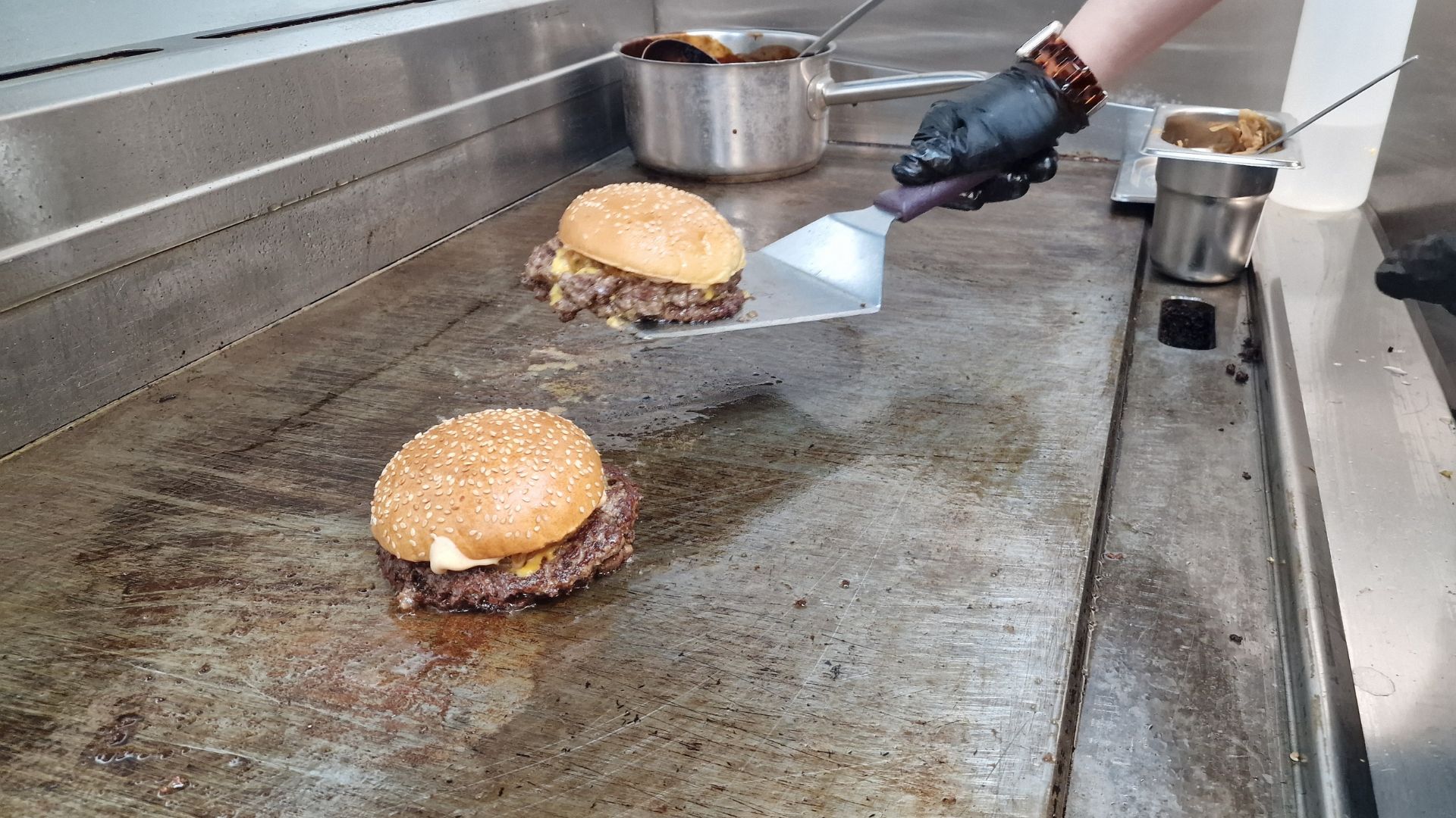 Finished smash burgers in buns getting taken off the grill