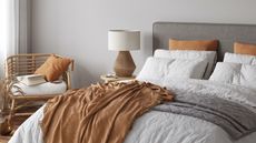 minimalist grey and orange bedroom with bed, nightstand and chair