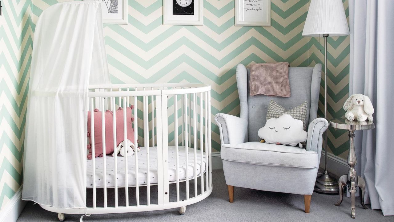 Colourful, fun nursery with green and white wallpaper, grey carpet and white cot. 