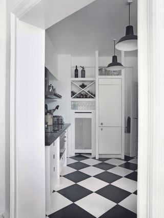 A small kitchen with chequered flooring and white cabinets