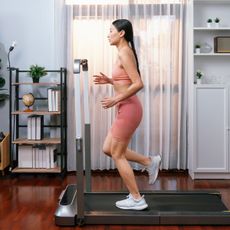 A woman doing a walking pad workout at home
