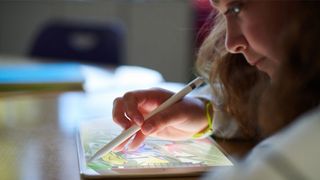 A girl using an Apple Pencil on an iPad