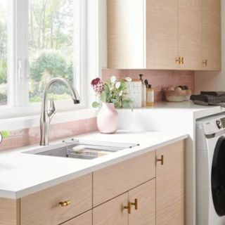 A pink laundry room with a sink and washing machine