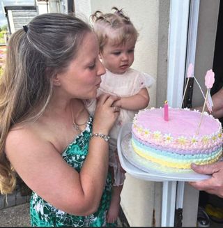 Sarah Myers holding Esme next to a birthday cake